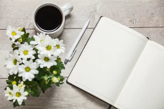 Sommerblomst på bord med en kopp kaffe og en notatbok